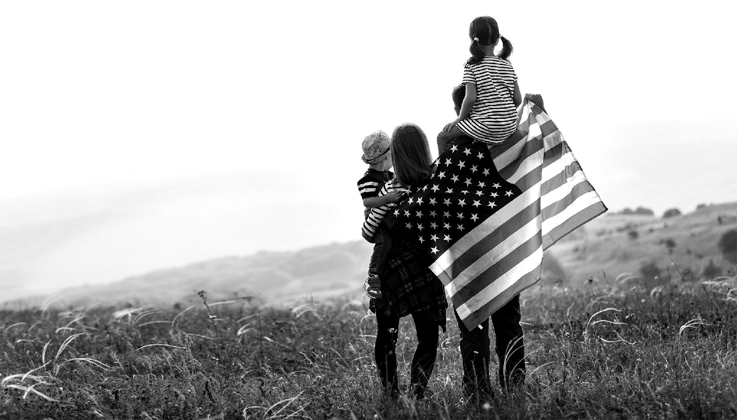 A family holding an American flag in a field
